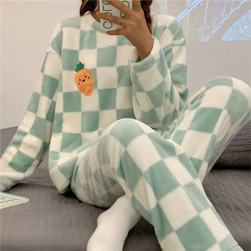 Femme portant un pyjama chaud à carreaux vert menthe et blanc, avec un motif brodé de carotte souriante sur le haut. Ensemble doux à manches longues avec pantalon assorti, idéal pour rester au chaud et confortable à la maison.