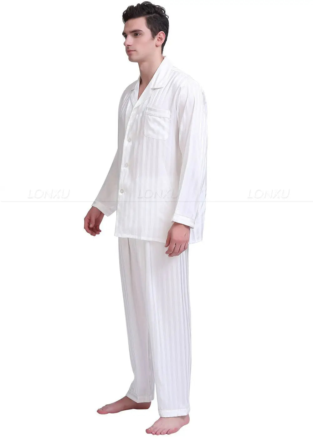 Pyjama homme Adrien en satin blanc, à rayures subtiles, avec une chemise à manches longues et un pantalon assorti. Le modèle le porte debout, affichant un look élégant et confortable, parfait pour une nuit de détente.