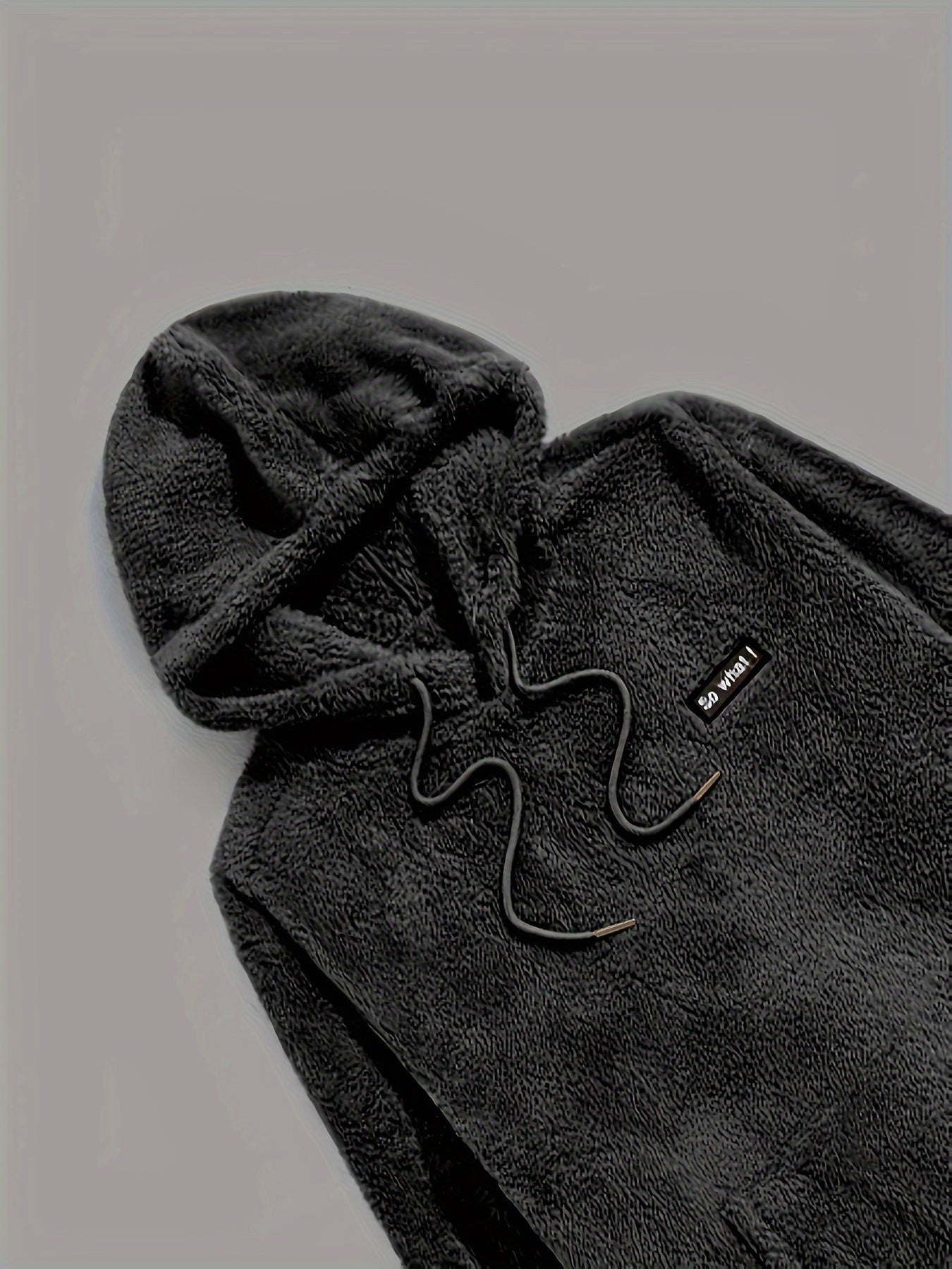 Haut de pyjama teddy noir pour homme avec capuche et cordon, fabriqué dans un tissu polaire doux et épais. Détail brodé sur la poitrine. Vêtement confortable et chaud, parfait pour l’hiver et les moments de détente à la maison.