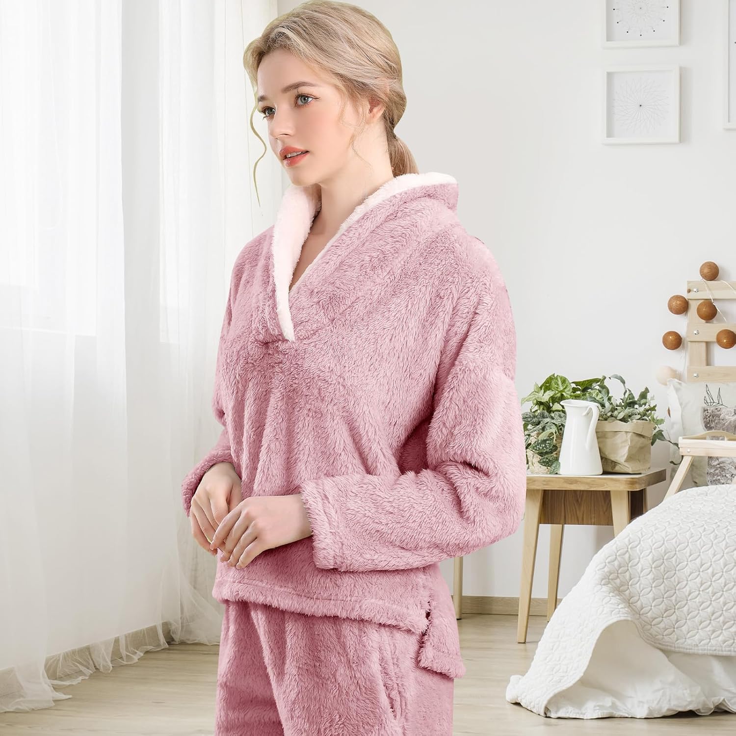 Femme portant un pyjama polaire rose poudré composé d’un haut doux à col large doublé en sherpa blanc et d’un pantalon assorti. Ensemble chaud, moelleux et très confortable, idéal pour l’hiver et les moments cocooning à la maison.