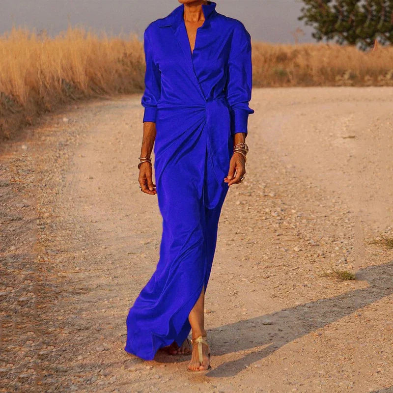Robe maxi en satin bleu vif, fluide et élégante, parfaite pour une soirée chic. Le design raffiné et sophistiqué avec une coupe asymétrique et une fente sur le côté met en valeur la silhouette avec élégance.