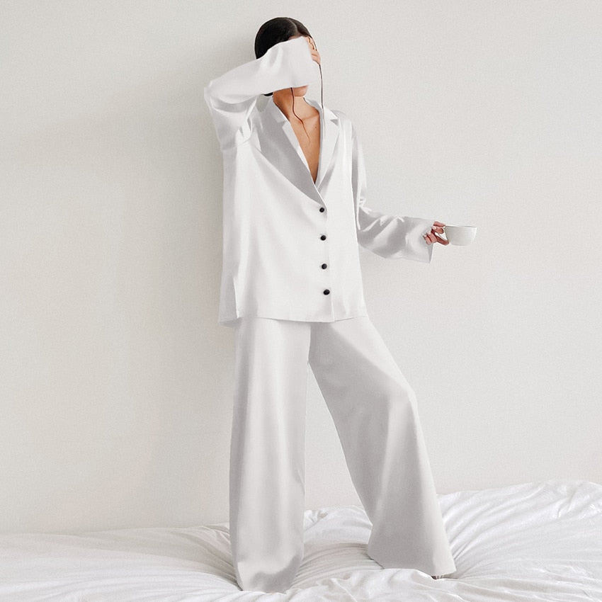 Pyjama femme Armelle blanc, ensemble deux pièces raffiné et confortable avec chemise fluide boutonnée à col tailleur et manches longues, pantalon large assorti, porté debout en intérieur, tissu satiné élégant.