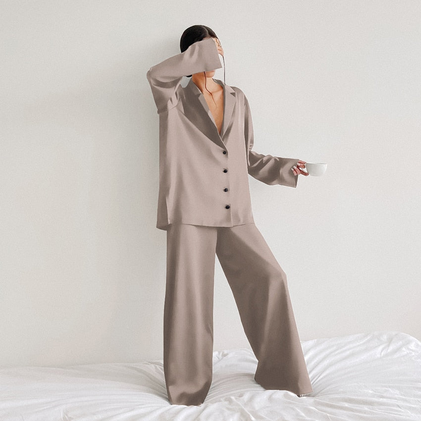 Pyjama femme Armelle beige taupe, ensemble deux pièces raffiné et confortable avec chemise fluide boutonnée à col tailleur et manches longues, pantalon large assorti, porté debout en intérieur, tissu satiné élégant.