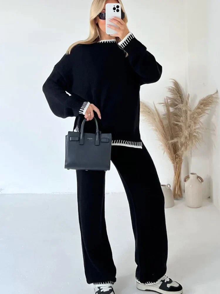 Femme prenant un selfie en miroir, portant un ensemble lounge noir avec finitions contrastantes blanches au col, poignets et ourlets. L’ensemble comprend un pull ample à manches longues et un pantalon fluide assorti. Style chic, confortable et moderne, parfait pour les journées cosy ou les sorties décontractées.