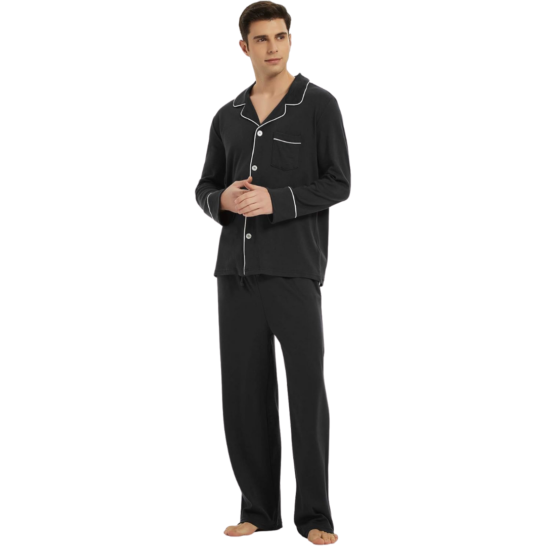 Homme debout portant un pyjama noir élégant avec haut boutonné à col revers et passepoils blancs, ainsi qu’un pantalon fluide assorti. Ensemble confortable et stylé, idéal pour la nuit ou les moments de détente à la maison.
