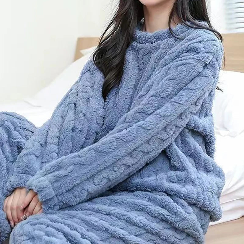 Femme assise sur un lit, portant le pyjama Camille en bleu pastel, au tissu ultra doux à effet torsadé. Un ensemble cosy, chaud et agréable, parfait pour se détendre avec style à la maison.
