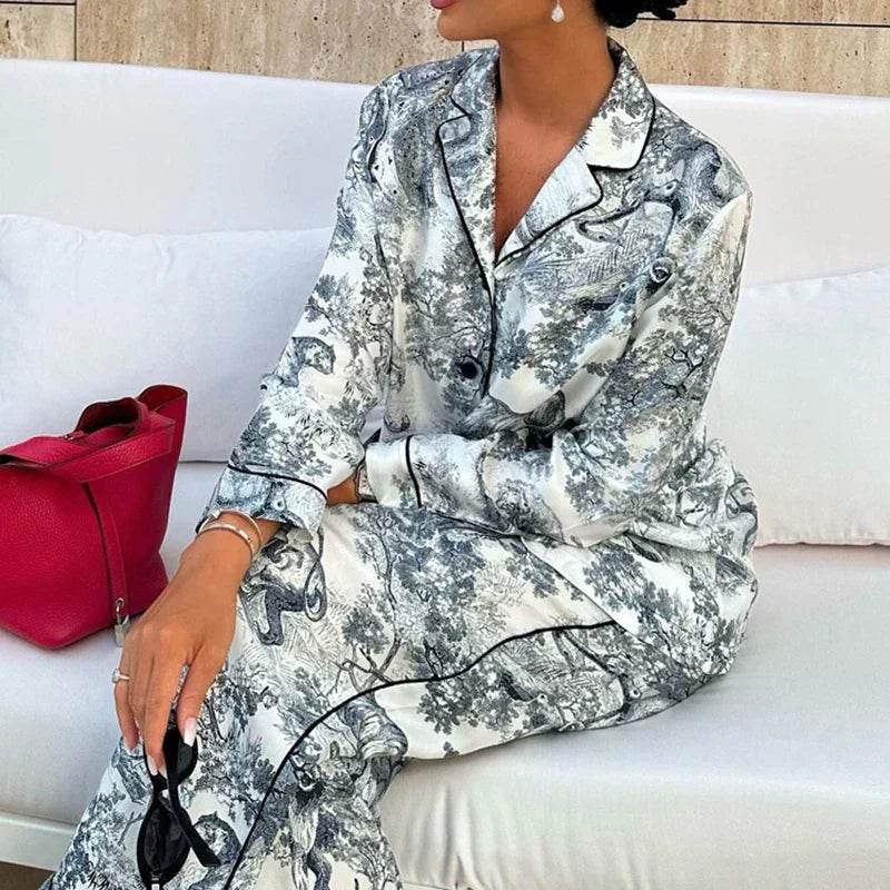 Gros plan du pyjama femme Charline gris imprimé toile de Jouy, chemise boutonnée à col tailleur et pantalon long assorti avec finitions passepoilées, tissu satiné élégant et confortable.