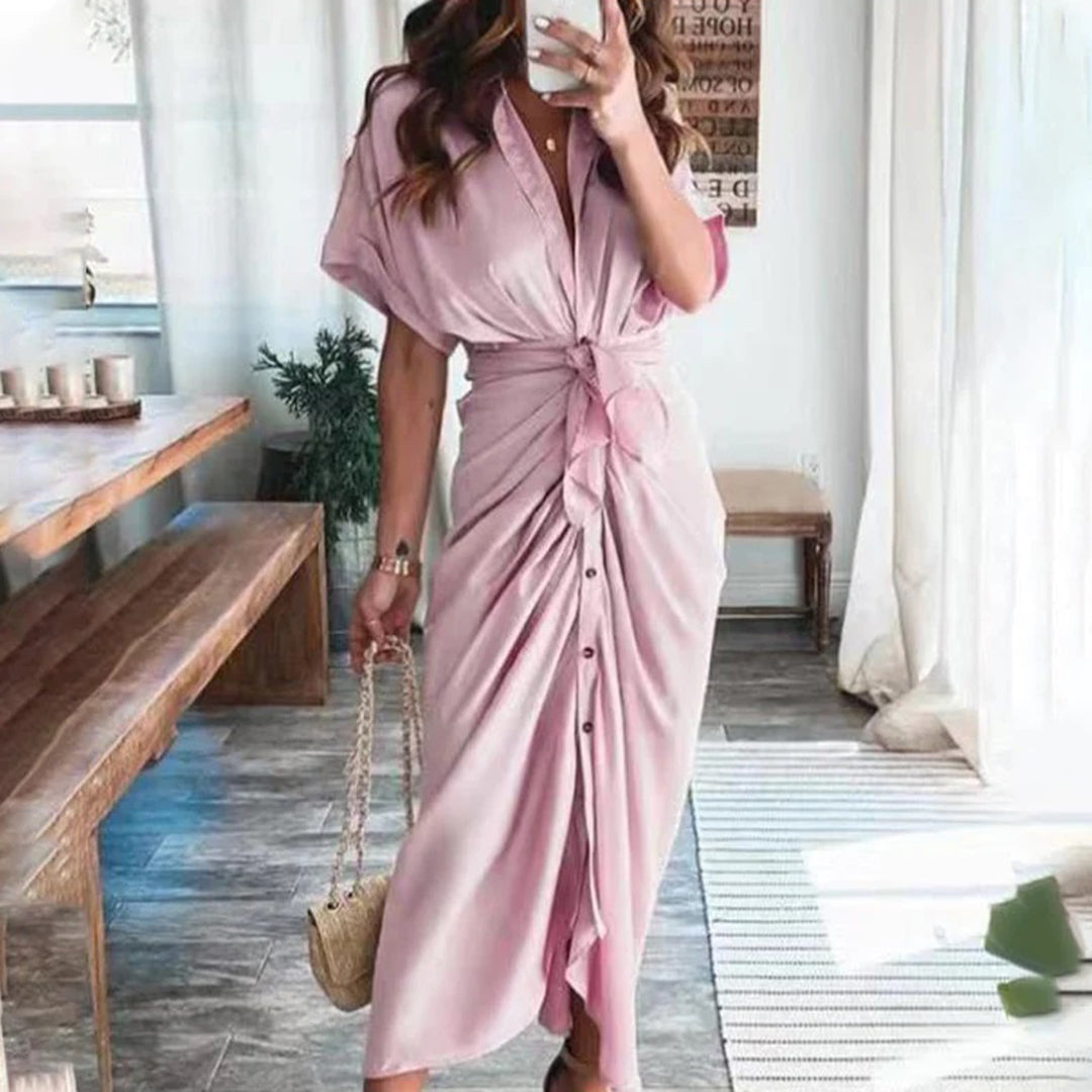 Apportez une touche d'élégance estivale avec la robe Deja en rose doux. Son design fluide avec un nœud central et des boutons à l'avant offre un look à la fois chic et décontracté, parfait pour les journées ensoleillées et les occasions estivales.