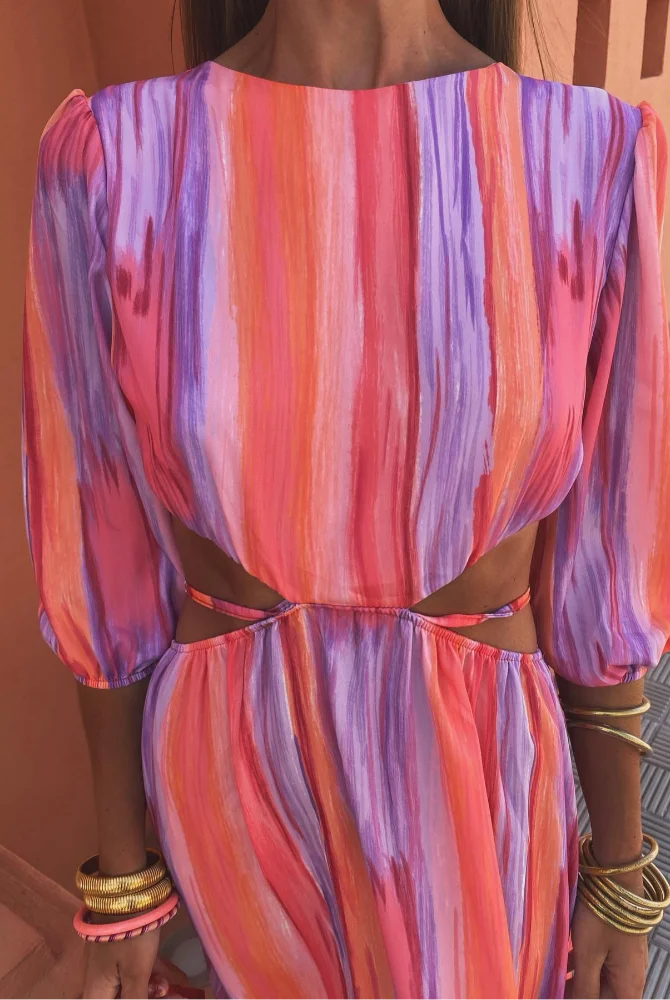 Zoom sur le haut de la robe maxi tie-dye pour femme, mettant en valeur le design coloré avec des teintes vives de rose, violet et orange. Les manches bouffantes et la coupe échancrée sur les côtés ajoutent une touche moderne et élégante, parfaite pour l'été.