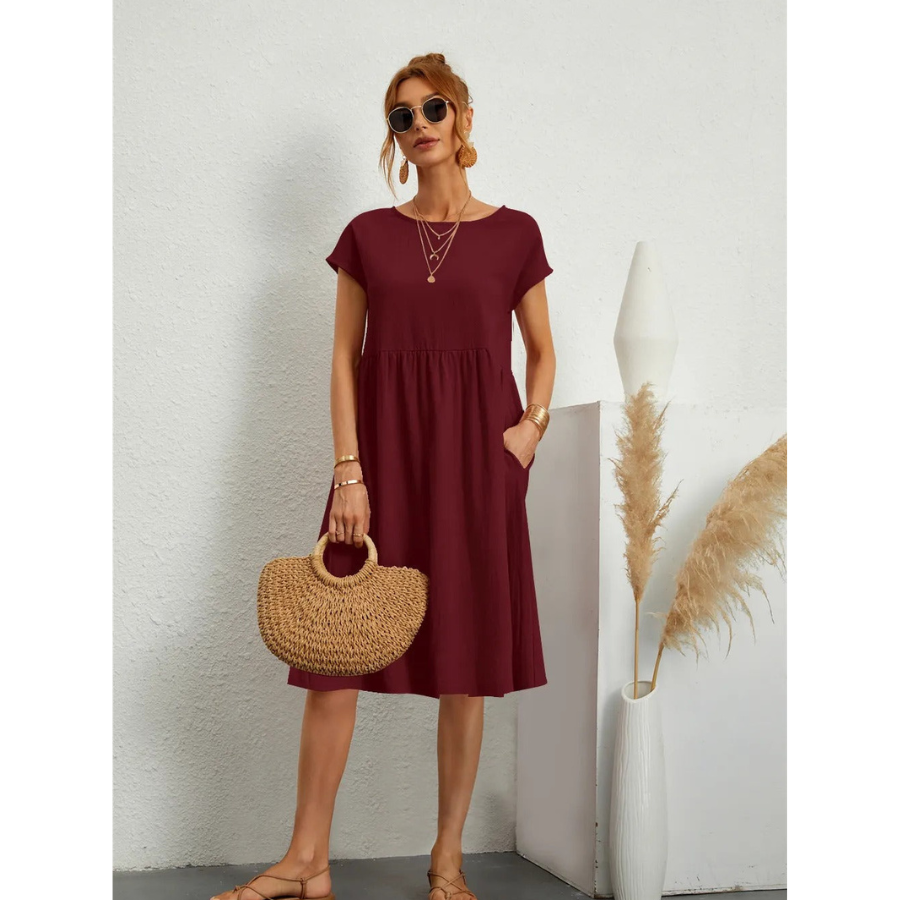 Élégante et confortable. Cette robe bordeaux à manches courtes, avec une coupe évasée et des poches latérales, allie confort et style. Accessoirisée avec un sac en osier, elle est parfaite pour un look décontracté et élégant lors des journées ensoleillées.