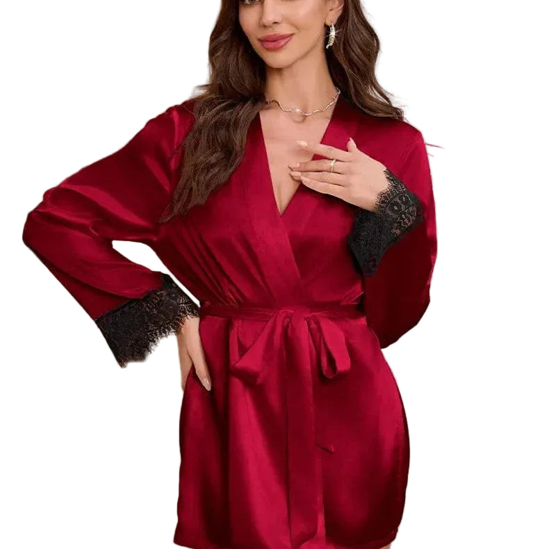 Kimono satin femme Évangéline couleur bordeaux, coupe courte avec ceinture à nouer, manches longues ornées de dentelle noire, porté par un modèle debout dans un intérieur élégant, vue de face.