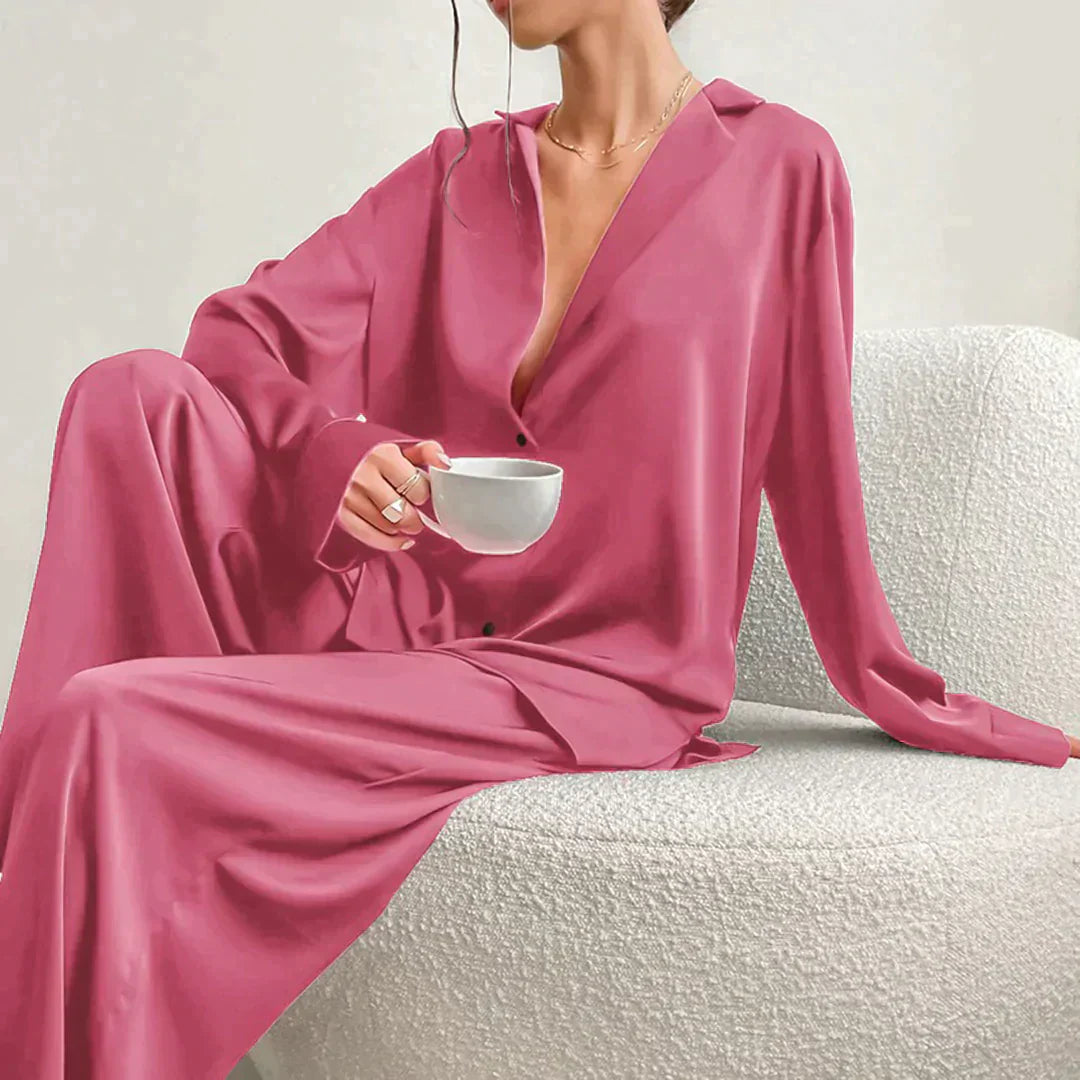 Femme portant le pyjama en coloris rose, un ensemble fluide et élégant avec chemise à col ouvert et pantalon ample. Pyjama doux, raffiné et confortable, idéal pour la nuit et les moments de détente.