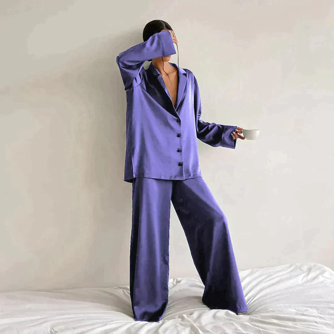 Femme portant le pyjama en coloris violet, un ensemble chic composé d’une chemise fluide à boutons et d’un pantalon ample. Pyjama doux, élégant et confortable, idéal pour la nuit et les moments de détente.