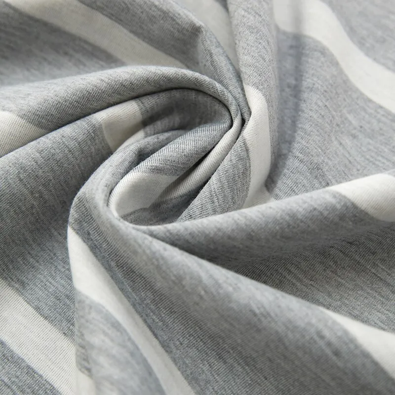 Gros plan sur le tissu du pyjama homme Henri, montrant une matière douce et légère en coton gris à rayures blanches, idéale pour un confort optimal pendant la nuit.