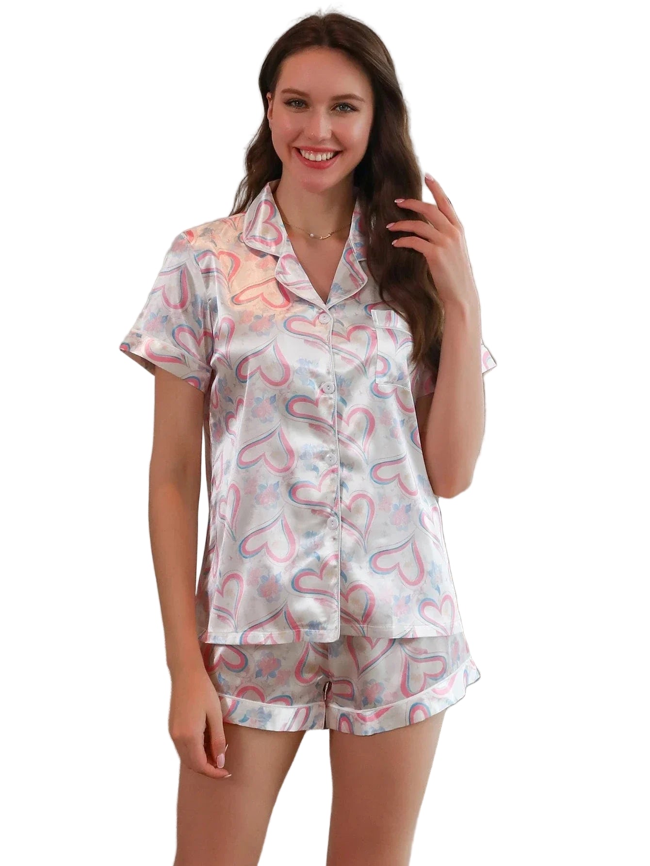 Femme portant le short de pyjama, un ensemble léger et confortable en satin blanc imprimé de cœurs roses et bleus, composé d’une chemise à manches courtes et d’un short assorti, photographiée dans un intérieur lumineux.