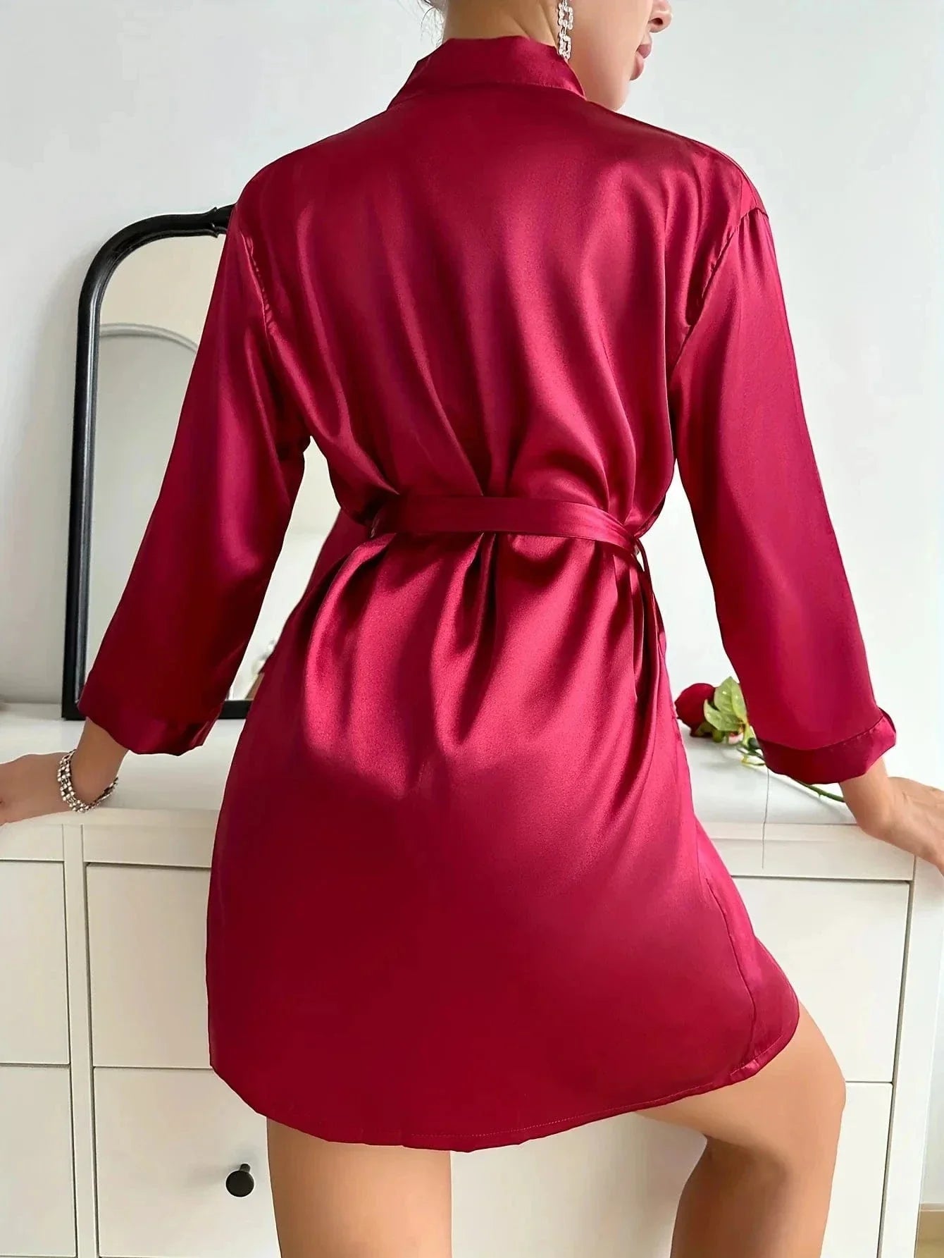 en satin rouge, ceinturé à la taille. Le tissu brillant et la coupe fluide soulignent l’élégance et le charme de ce modèle idéal pour la nuit.