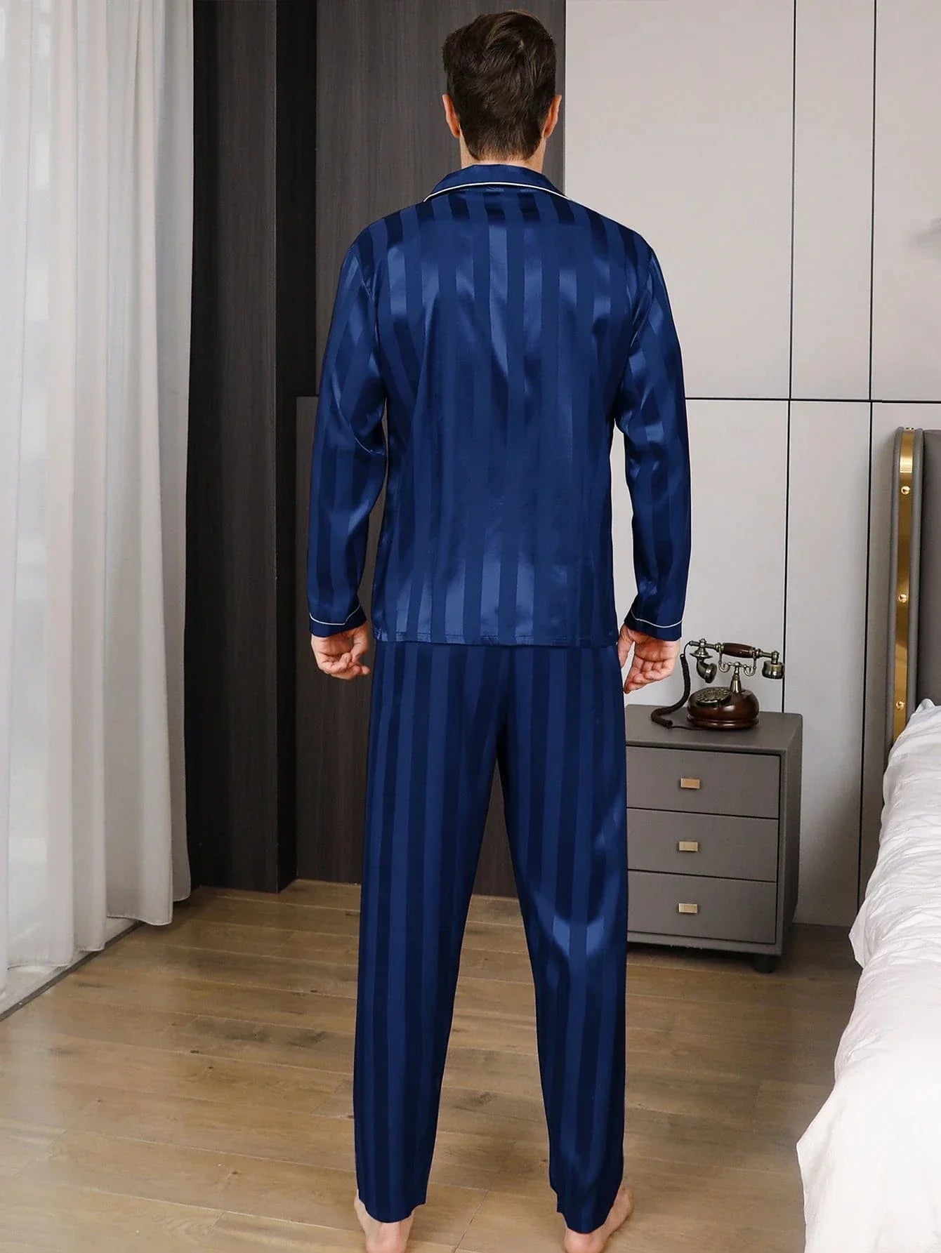 Vue de dos d’un homme portant le pyjama satin pour homme Jérôme, ensemble élégant et confortable en satin bleu à fines rayures, composé d’une chemise à manches longues et d’un pantalon assorti, offrant une coupe soignée et un tombé fluide idéal pour la nuit ou la détente à la maison.