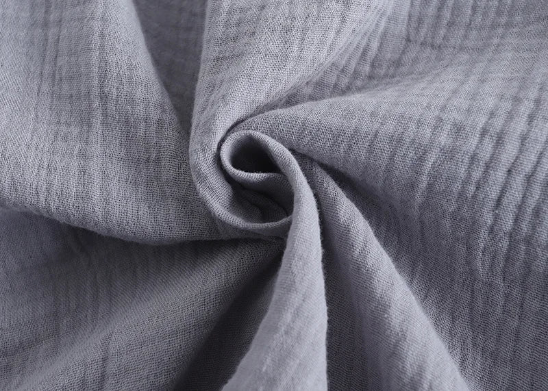 Gros plan sur le tissu gris clair gaufré du pyjama homme, montrant une matière douce, légère et respirante, idéale pour un confort optimal jour et nuit.