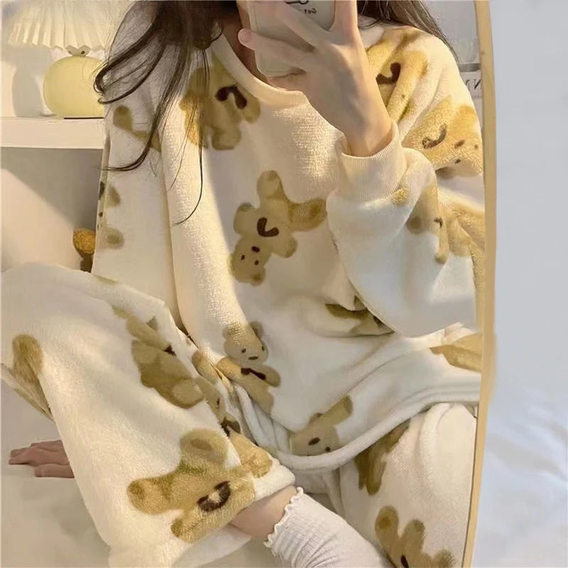 Femme portant un pyjama moelleux blanc cassé imprimé de petits oursons beiges. Ensemble composé d’un haut à manches longues et d’un pantalon assorti, idéal pour rester au chaud et se détendre confortablement à la maison.