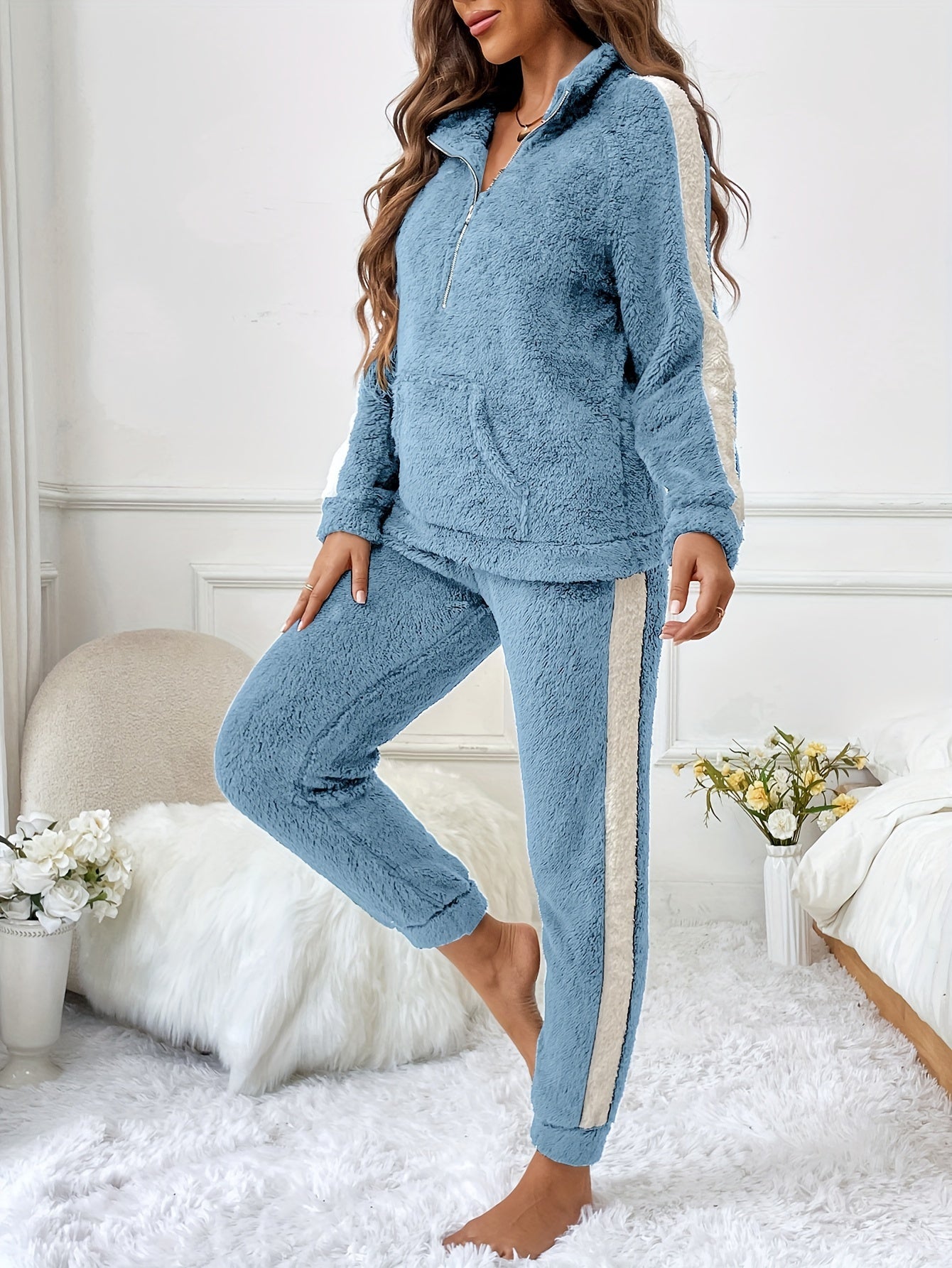 Femme portant un pyjama deux pièces bleu ciel en polaire douce avec des bandes blanches contrastantes sur les manches et les jambes, idéal pour des moments cocooning au chaud à la maison.