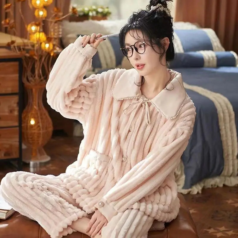 Femme portant un pyjama en flanelle rose pâle, composé d’un haut texturé à large col décoré de perles et d’un pantalon assorti. Ensemble chaud, doux et très élégant, idéal pour l’hiver et les moments cocooning à la maison.