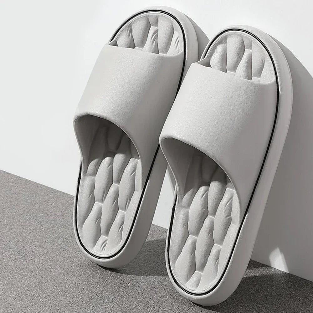 Paire de chaussons unisexes blancs avec large bride et semelle intérieure matelassée, offrant un confort moelleux. Design épuré avec semelle antidérapante, idéal pour marcher en toute sécurité à la maison.