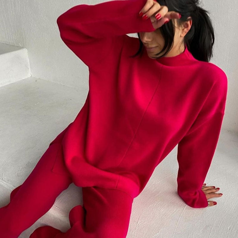 Femme assise portant l’ensemble Naïla couleur fuchsia, composé d’un pull chaud à col montant et manches longues, assorti à un pantalon confortable. Tenue douce, chaude et décontractée, parfaite pour rester stylée tout en ayant chaud à la maison ou en extérieur.
