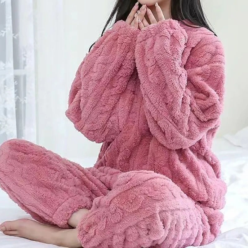 Femme assise sur un lit, portant un pyjama polaire rose à texture torsadée, composé d’un haut manches longues et d’un pantalon assorti. Ensemble chaud, ultra doux et confortable, parfait pour affronter l’hiver avec style et bien-être.