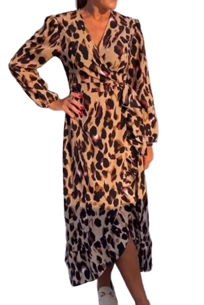 Femme portant une robe longue à imprimé léopard avec des manches longues, une taille ceinturée et une fente sur le côté, sur une terrasse ensoleillée.