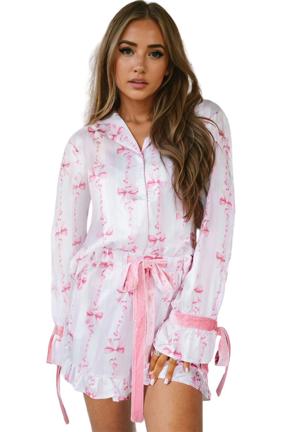 Pyjama femme Pascale blanc à motifs nœuds roses, chemise boutonnée à manches longues avec poignets noués, short assorti et ceinture à nouer, style élégant et raffiné en tissu léger.