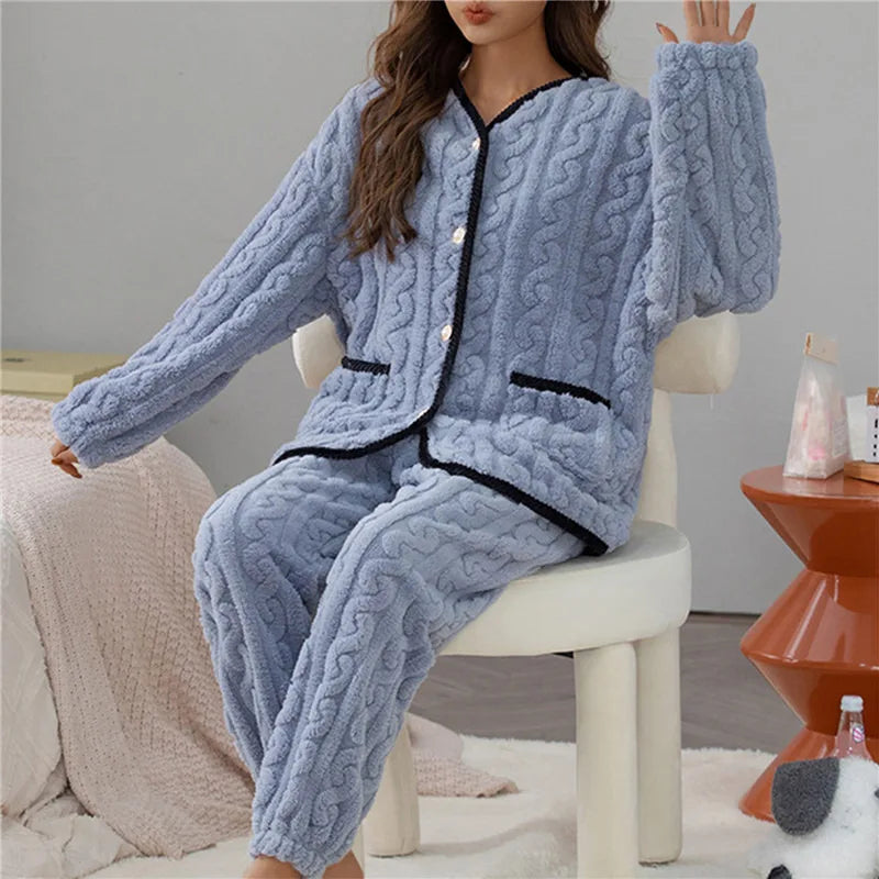 Femme portant le pyjama Percival, un ensemble d’hiver doux et chaud en tissu peluche bleu clair, composé d’un haut boutonné à manches longues avec bordures noires et d’un pantalon assorti, parfait pour rester confortable et au chaud à la maison.