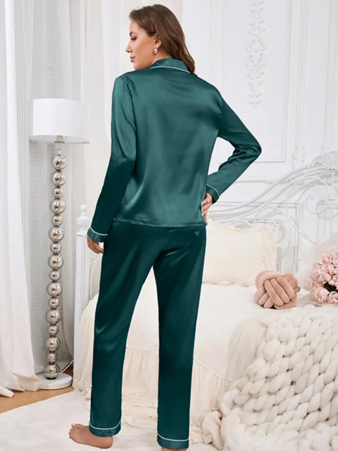Vue arrière d’une femme portant un pyjama en satin vert émeraude, composé d’un haut à manches longues avec col à revers et d’un pantalon assorti avec passepoils clairs. Ensemble élégant, doux et agréable à porter, idéal pour les soirées détente avec style.