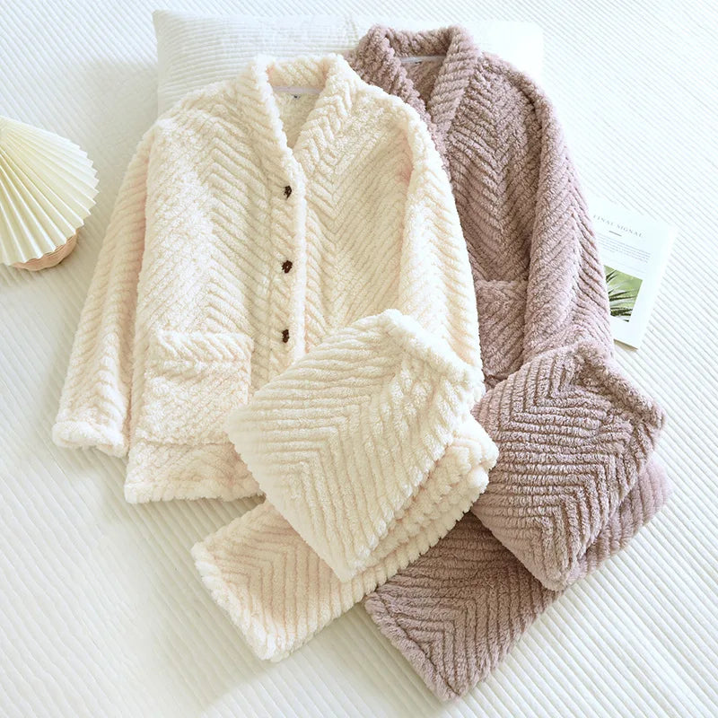 Deux pyjamas femme en tissu pelucheux à motif chevron posés sur un lit : un en beige écru avec boutons foncés, l’autre en rose taupe. Chaque ensemble comprend une veste à poches et un pantalon assorti. Pyjamas épais, doux et parfaits pour l’hiver ou les moments cocooning.