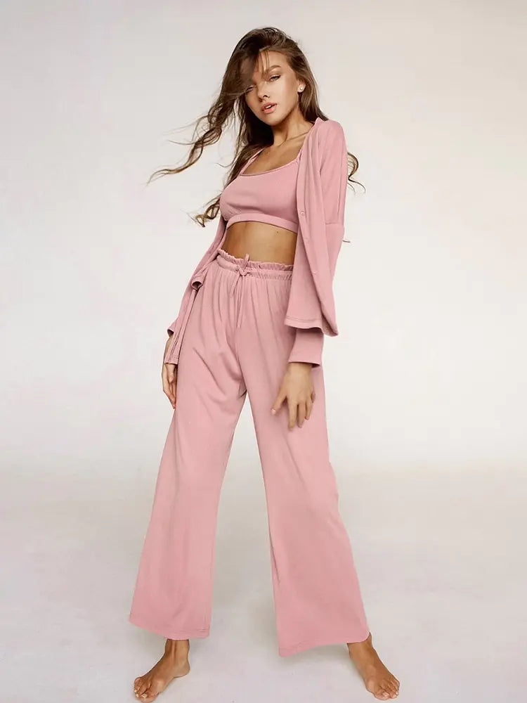 Femme portant un ensemble nuisette rose, composé d'un top sans manches et d'un pantalon fluide à taille élastiquée. Elle porte également une veste légère assortie, créant un look à la fois élégant et décontracté. Elle pose avec une attitude confiante, mettant en valeur le confort et la simplicité de cet ensemble chic.