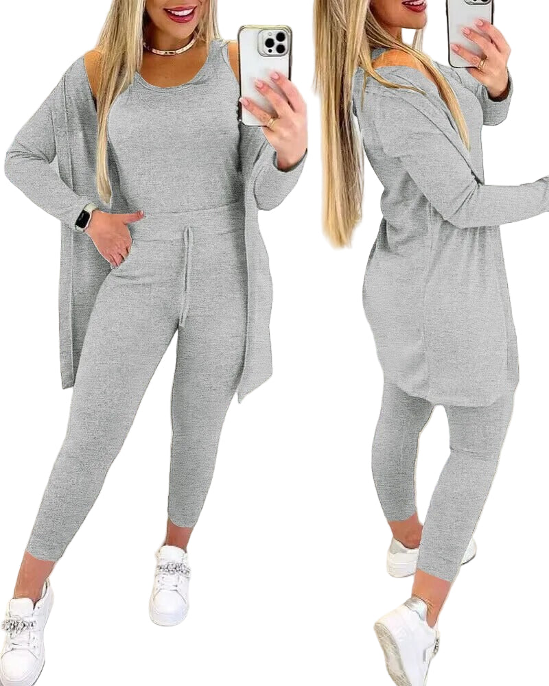 Femme portant l'ensemble Axelle en gris clair, composé d’un débardeur ajusté, d’un legging taille haute avec cordon de serrage et d’un long cardigan assorti. Tenue confortable et stylée, idéale pour des moments de détente à la maison ou un look décontracté en extérieur.