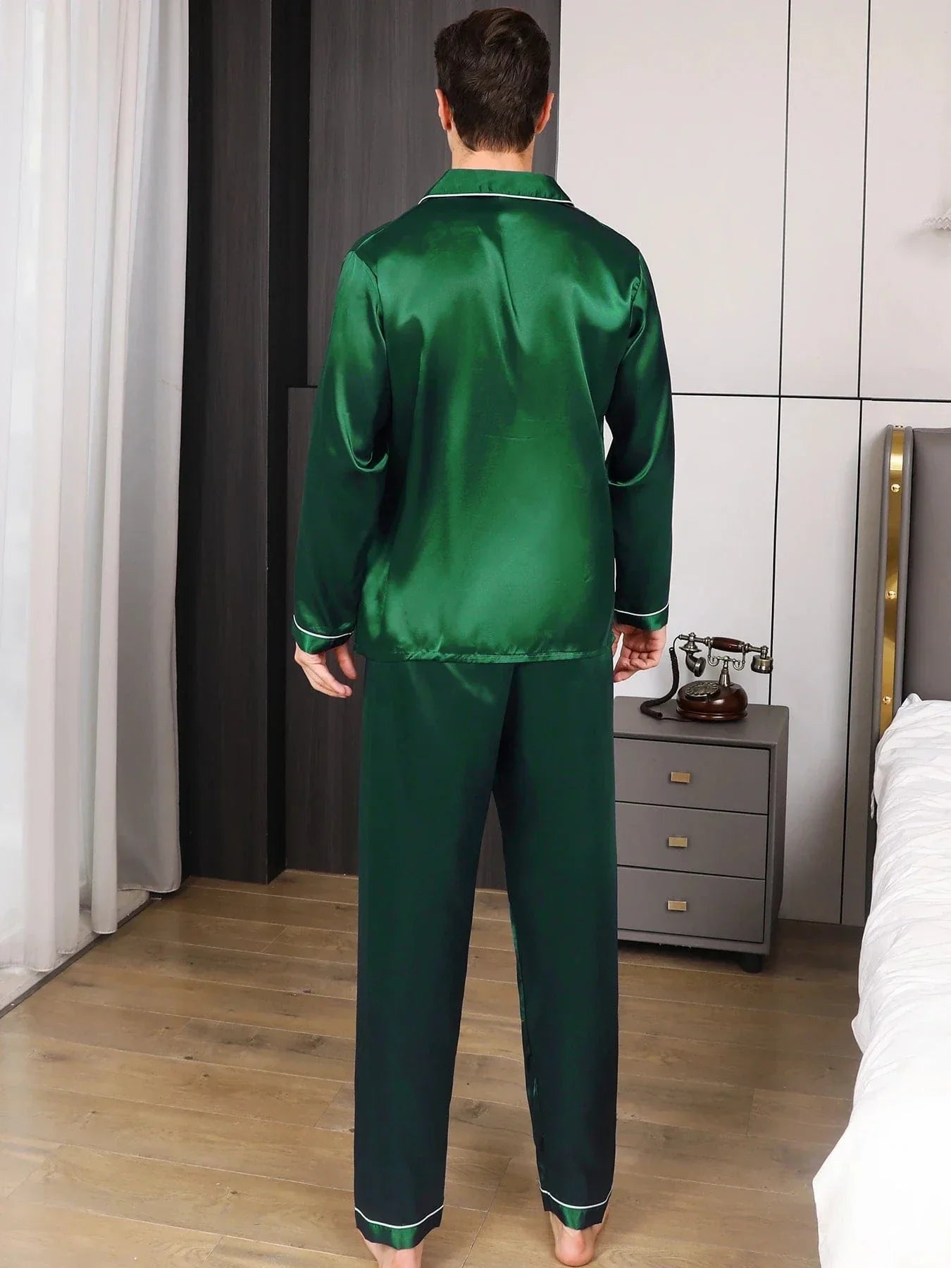 Vue arrière du pyjama en satin pour homme, avec une chemise vert émeraude et un pantalon assorti. Ce pyjama élégant et confortable est parfait pour des moments de détente à la maison. Le design simple mais raffiné, avec des finitions blanches sur les poignets et le bas du pantalon, ajoute une touche de sophistication. Le modèle porte le pyjama avec aisance dans un cadre moderne et élégant.