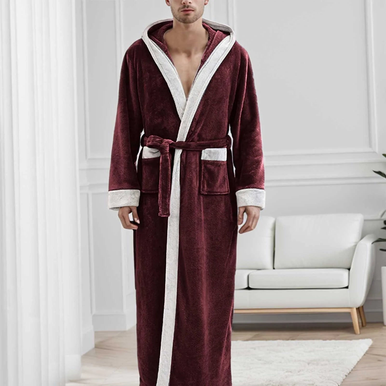 Homme portant le peignoir Étienne, modèle chaud et idéal pour l’hiver en tissu bordeaux doux avec bordures crème et ceinture assortie, présenté dans un intérieur moderne et lumineux.