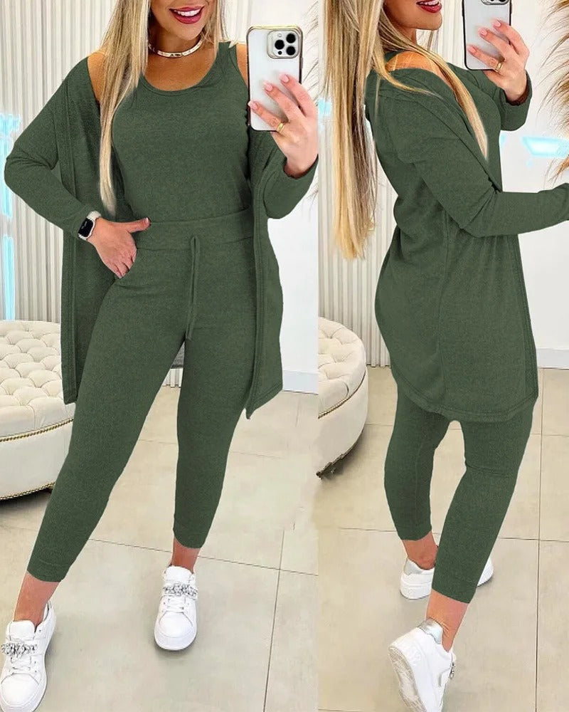 Femme portant l’ensemble Axelle vert kaki, composé d’un débardeur, d’un legging taille haute avec lien à nouer et d’un long cardigan fluide assorti. Une tenue cosy, moderne et stylée, idéale pour les moments de détente à la maison ou les sorties décontractées.