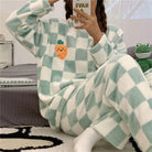 Femme portant un pyjama chaud à carreaux vert menthe et blanc, orné d’un motif brodé de carotte souriante sur le haut. Ensemble à manches longues et pantalon assorti, idéal pour le confort et la détente à la maison.