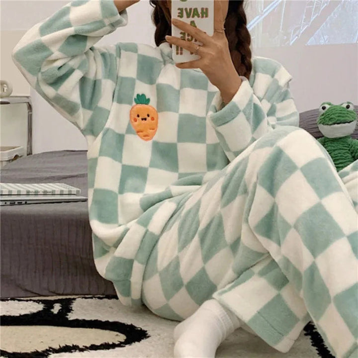 Femme portant un pyjama chaud à carreaux vert menthe et blanc, orné d’un motif brodé de carotte souriante sur le haut. Ensemble à manches longues et pantalon assorti, idéal pour le confort et la détente à la maison.