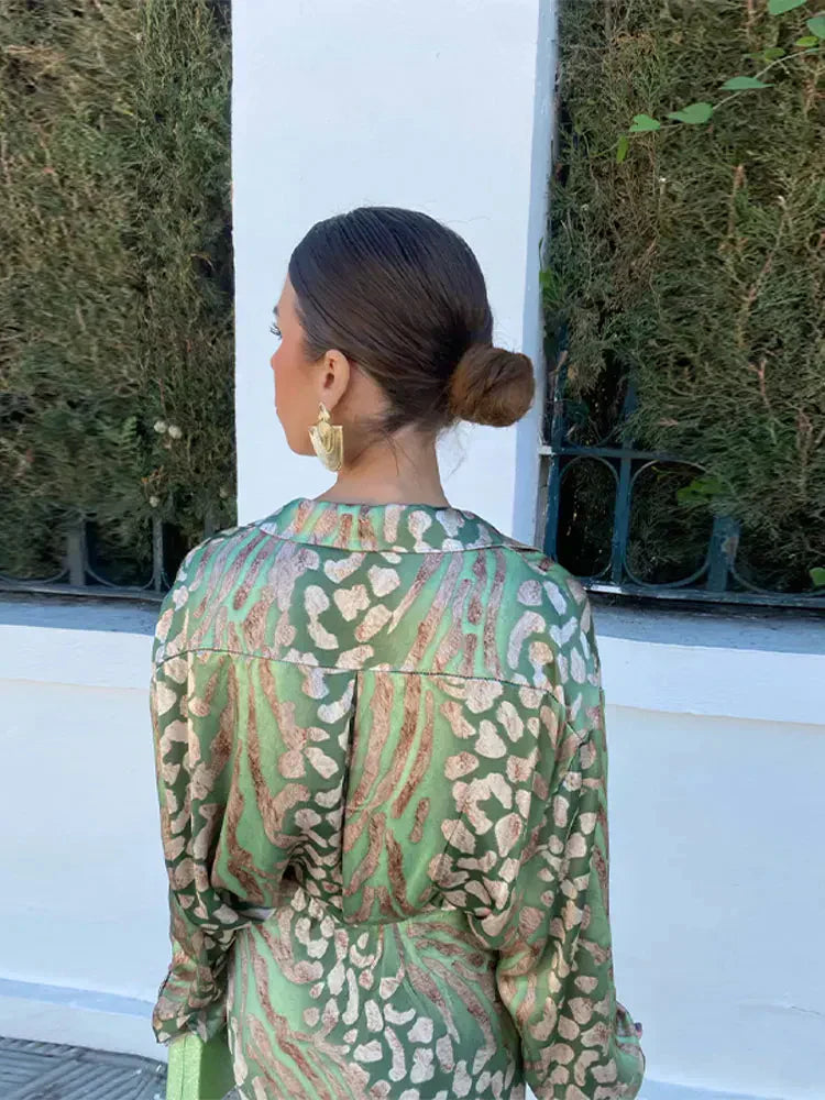 Vue arrière de la robe d'été Aélia pour femmes, élégante et raffinée, avec un imprimé vert et or. Parfaite pour l'été, cette robe assure un look chic et tendance, accompagnée d'accessoires dorés.