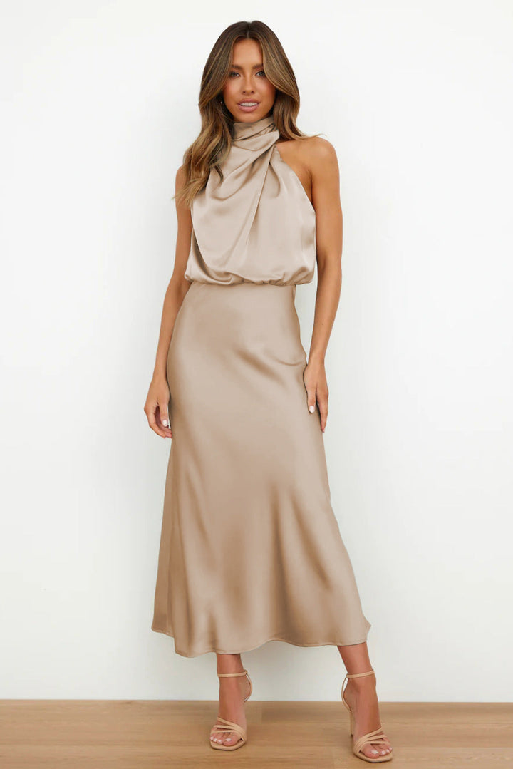 Cette robe longue de couleur beige, au tissu satin doux et brillant, offre une coupe chic et fluide. Avec son décolleté drapé et sa silhouette fluide, elle est idéale pour des événements estivaux raffinés.