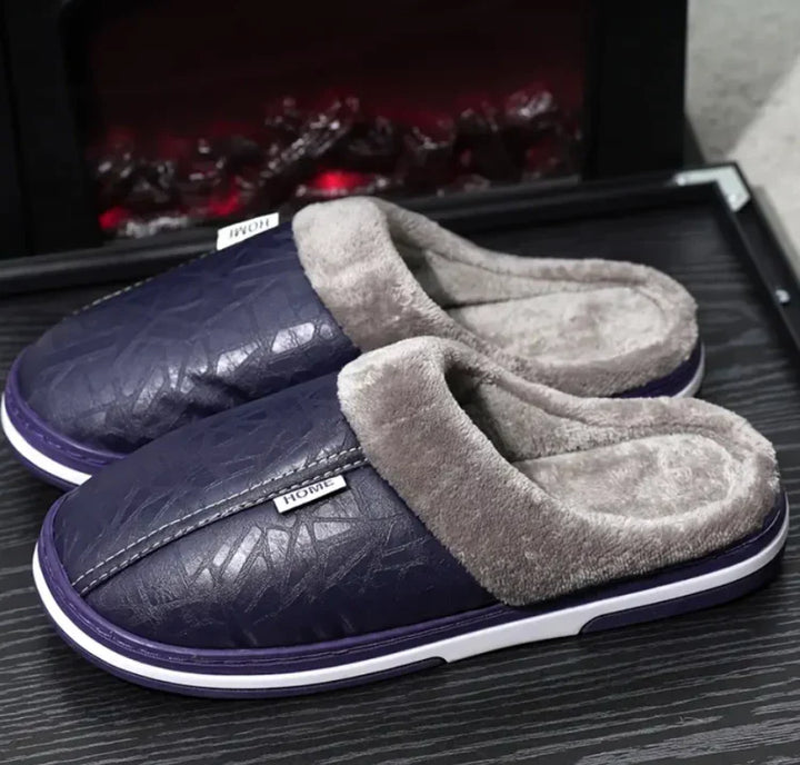 Chaussons homme Alan bleu marine, style pantoufles fermées avec effet cuir, col et intérieur doublés en fausse fourrure grise, semelle épaisse confortable pour garder les pieds au chaud à la maison.