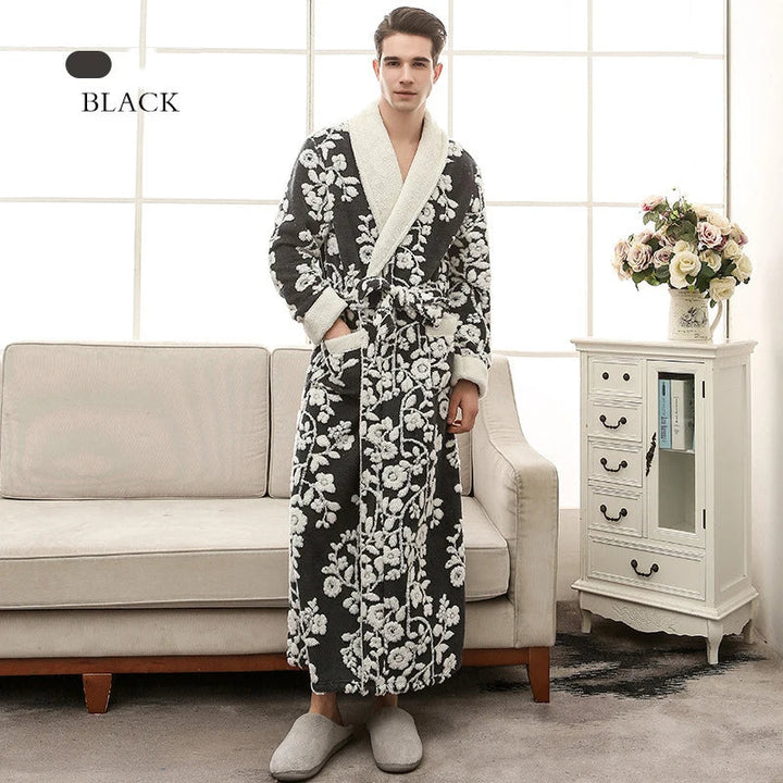 Homme portant le peignoir en coloris noir, long et chaud, orné de motifs floraux blancs, avec col châle doux et ceinture assortie. Peignoir élégant et confortable, idéal pour un usage quotidien à la maison.