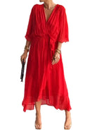 Femme portant une robe rouge fluide en chiffon, avec une coupe élégante, manches 3/4 et taille marquée, dans un environnement moderne et raffiné.