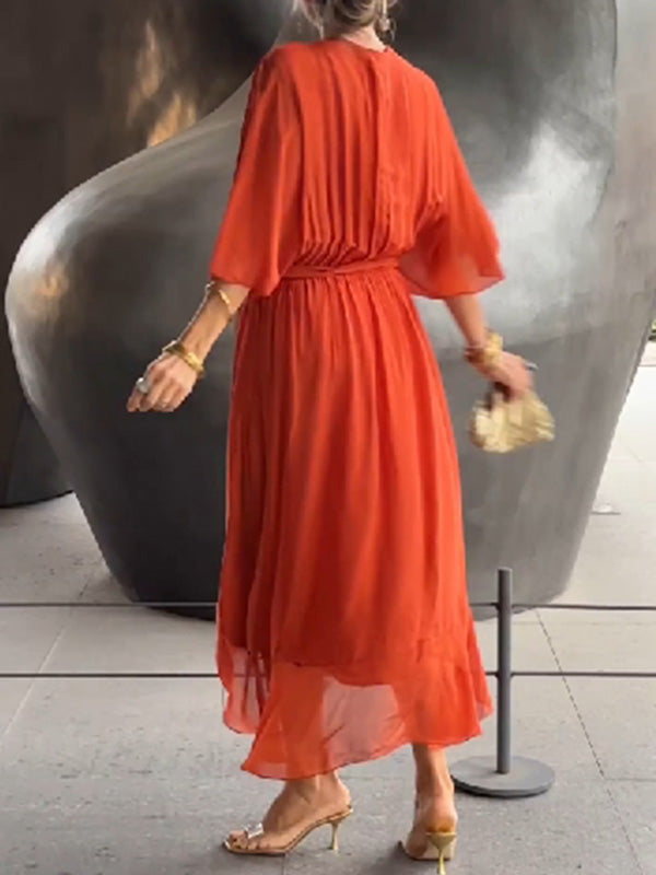 Femme vue de dos portant une robe chiffon rouge vif, avec une taille élastiquée, et des accessoires dorés tels qu&