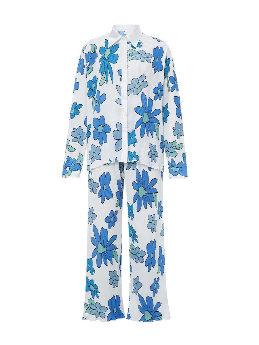 Pyjama féminin léger et confortable avec un design coloré et floral. Le haut à manches longues et le pantalon fluide sont ornés de grandes fleurs bleues et vertes sur fond blanc. Ce pyjama à l’allure rétro est parfait pour des moments de détente avec style.