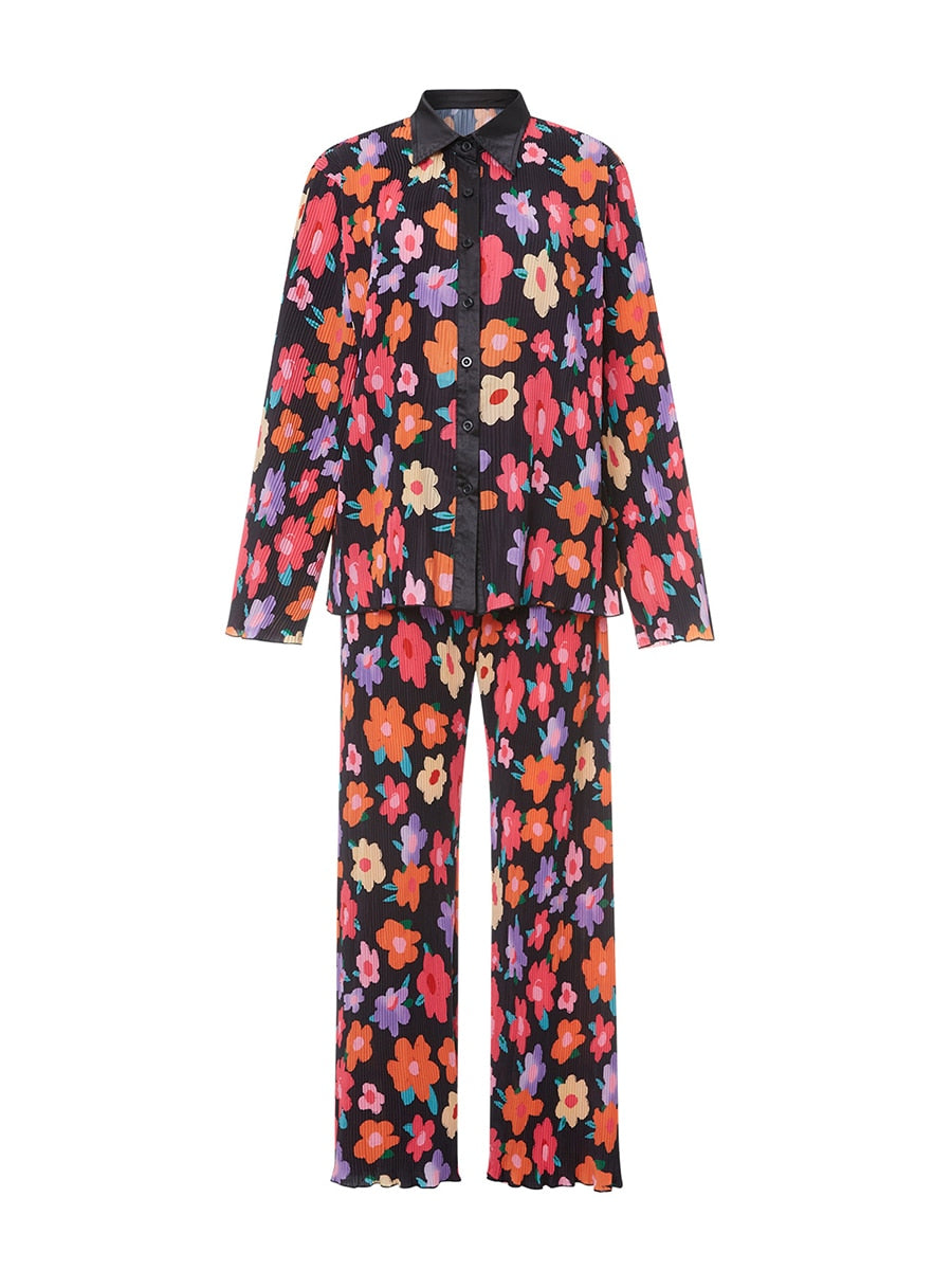 Pyjama femme à fleurs colorées sur fond noir, composé d'une chemise à boutons à manches longues et d'un pantalon ample assorti. Le design éclatant et moderne, alliant confort et légèreté, en fait une tenue parfaite pour se détendre avec style.