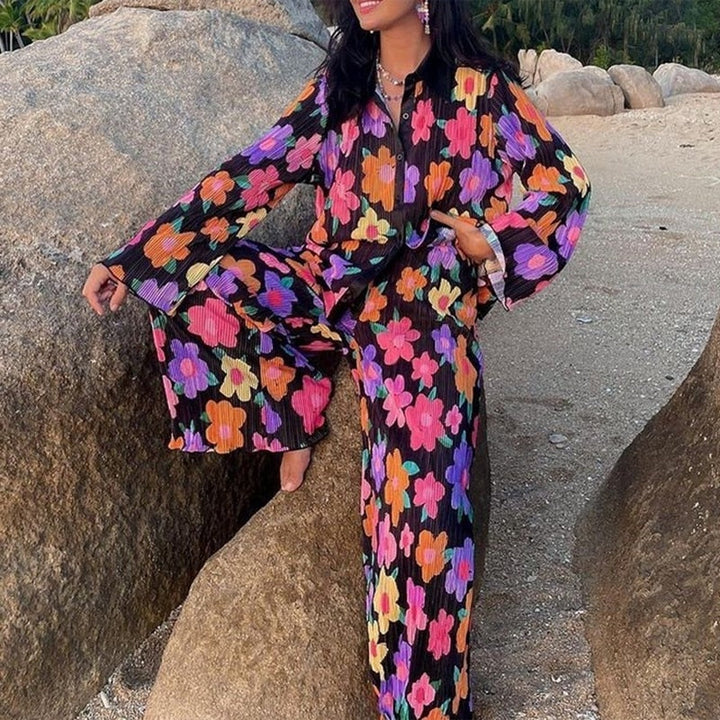 Pyjama femme à fleurs colorées sur fond noir, comprenant une chemise à boutons et un pantalon ample assorti. Le design vibrant et léger assure confort et élégance, idéal pour une tenue décontractée et stylée en toute occasion.