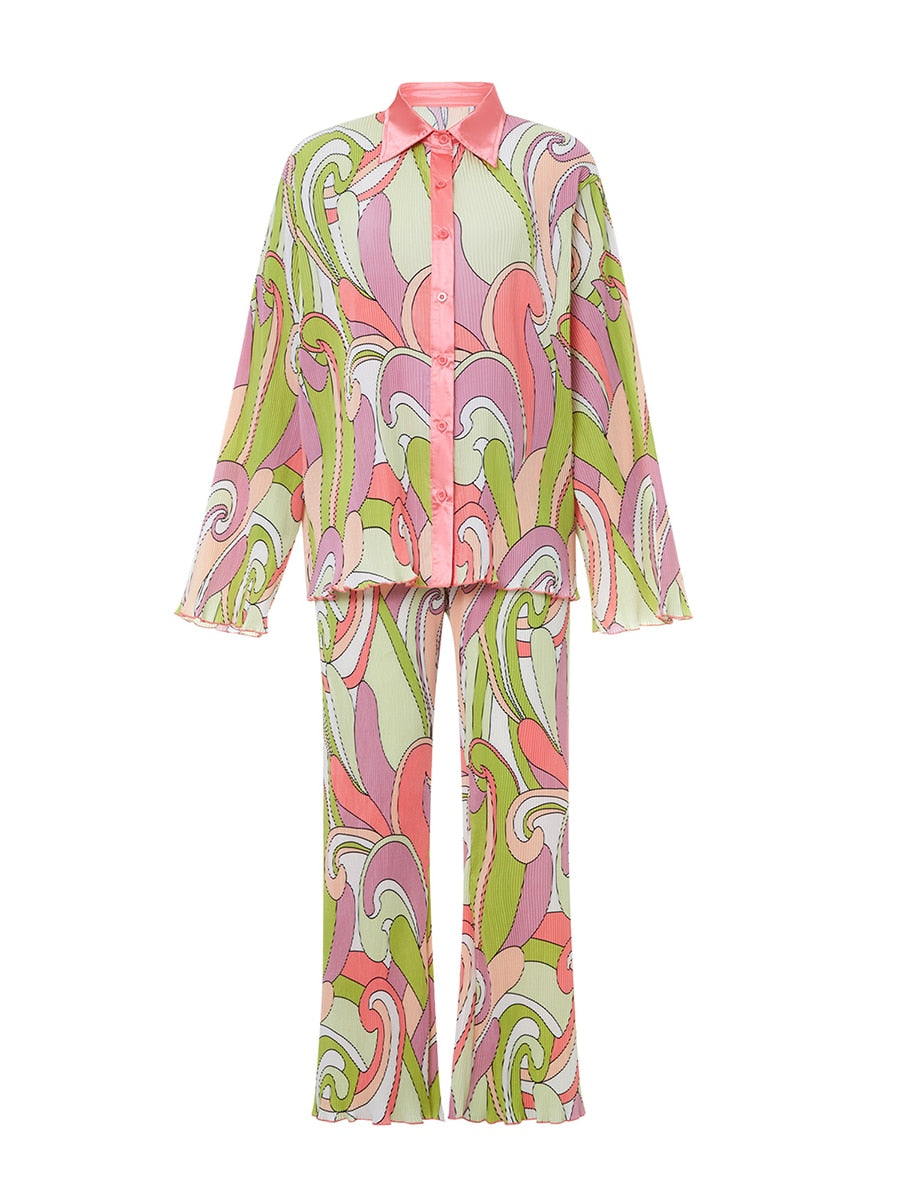 Pyjama féminin léger et confortable avec un motif rétro aux couleurs pastel. Le haut à manches longues est rose pâle avec un col satiné, et le bas assorti est à motifs fluides dans des teintes de vert, rose et violet. Le tissu est léger et doux, idéal pour un confort optimal.
